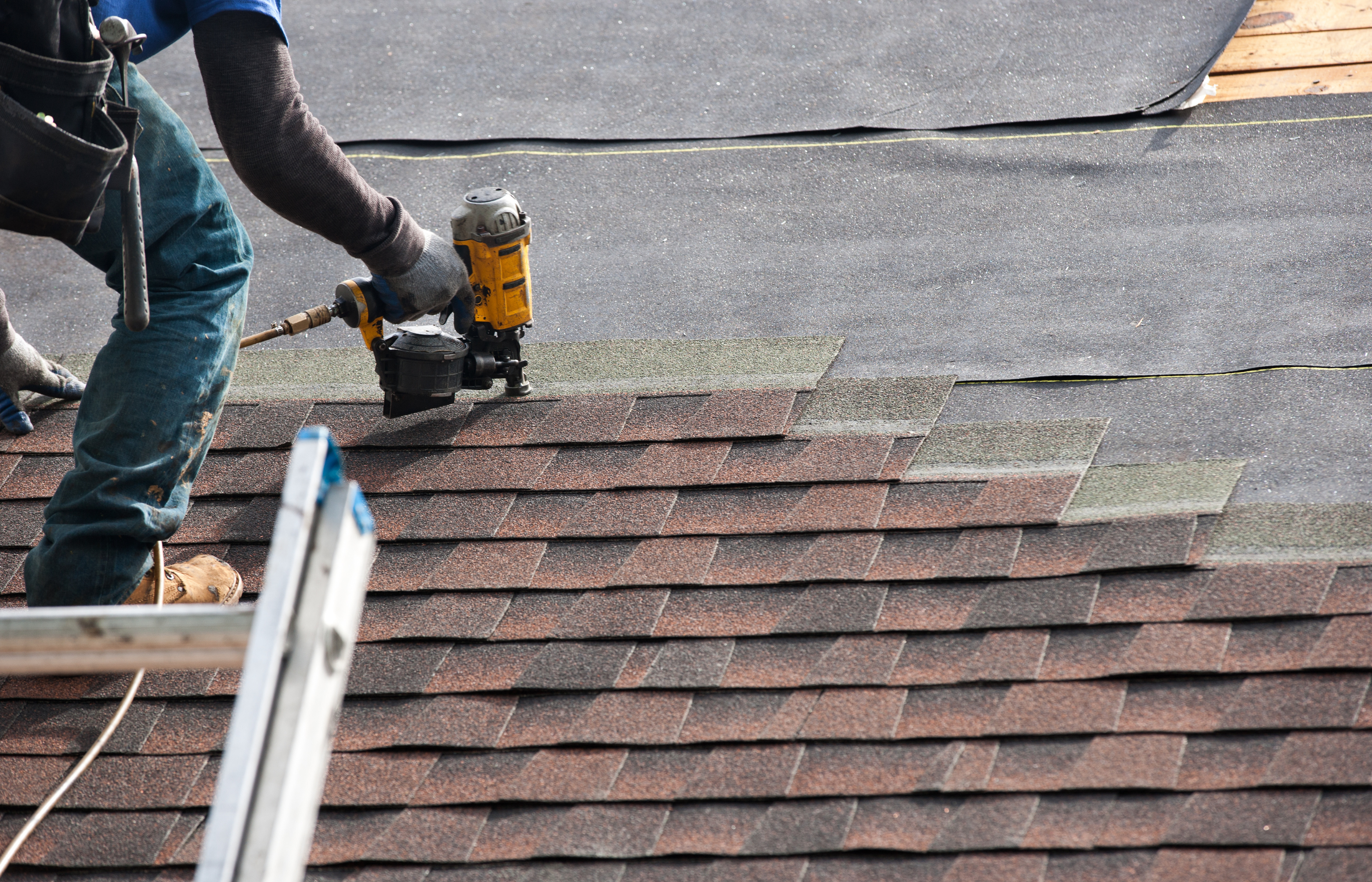 3 Picture of a roofer replacing a brown asphalt shingle roof.